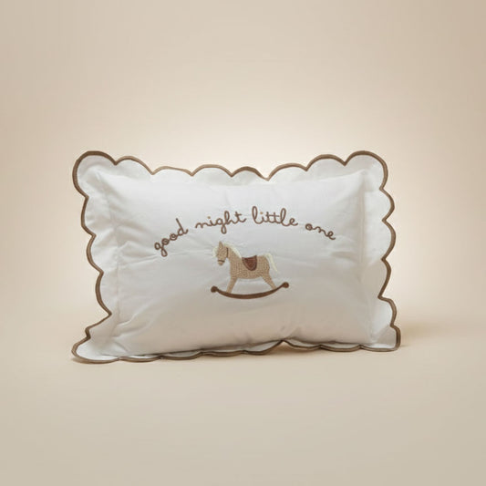 Decorative pillow with 'good night little one' text and rocking horse design on a beige background